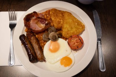 Yumurtalı tam İngiliz kahvaltısı, kızarmış pastırma, sosis, fasulye, tost, mantar, ızgara domates, klasik yemek, geleneksel İngiliz sabah yemeği.