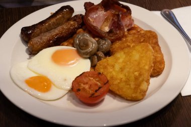 Yumurtalı tam İngiliz kahvaltısı, kızarmış pastırma, sosis, fasulye, tost, mantar, ızgara domates, klasik yemek, geleneksel İngiliz sabah yemeği.