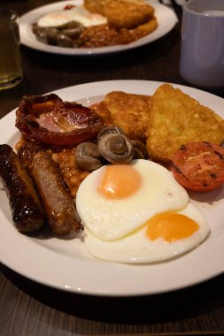 Yumurtalı tam İngiliz kahvaltısı, kızarmış pastırma, sosis, fasulye, tost, mantar, ızgara domates, klasik yemek, geleneksel İngiliz sabah yemeği.