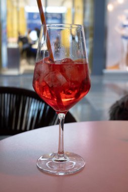 Bir bardak Aperol Spritz içeceği İtalya 'da yağmurda, küçük bir sokak kafesinde, yağmurlu bir sokakta ve dükkanların ışıklarında servis edilir.