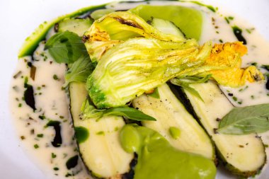 Fransız restoranında şefle güzel bir akşam yemeği. Ana vejetaryen yemeği. Genç kabak kabakları, çiçekler, taze sürüler ve beyaz krema sosu.