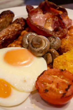 Yumurtalı tam İngiliz kahvaltısı, kızarmış pastırma, sosis, fasulye, tost, mantar, ızgara domates, klasik yemek, geleneksel İngiliz sabah yemeği.