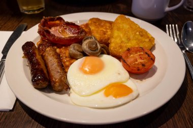 Yumurtalı tam İngiliz kahvaltısı, kızarmış pastırma, sosis, fasulye, tost, mantar, ızgara domates, klasik yemek, geleneksel İngiliz sabah yemeği.