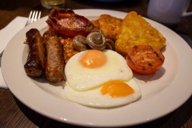 Yumurtalı tam İngiliz kahvaltısı, kızarmış pastırma, sosis, fasulye, tost, mantar, ızgara domates, klasik yemek, geleneksel İngiliz sabah yemeği.