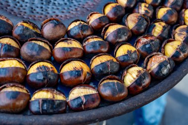 Geleneksel Fransız yemek ekipmanları ateşte taze kestane kızartır ve ızgara yapar. Lezzetli sokak yemekleri, sonbaharda Paris sokaklarında fındık yemek.