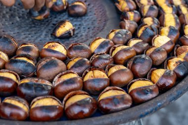 Geleneksel Fransız yemek ekipmanları ateşte taze kestane kızartır ve ızgara yapar. Lezzetli sokak yemekleri, sonbaharda Paris sokaklarında fındık yemek.