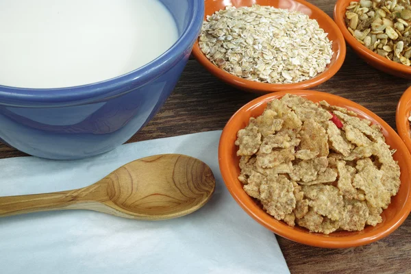Cuatro tazones pequeños con diferentes cereales y un tazón con leche — Foto de Stock