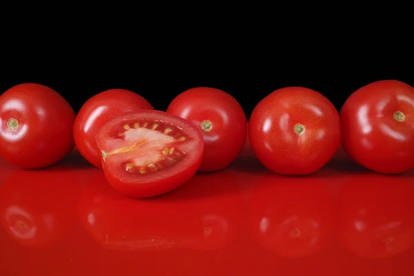 Свежие красные цыганские помидоры на красном столе и черном фоне, прием — стоковое фото