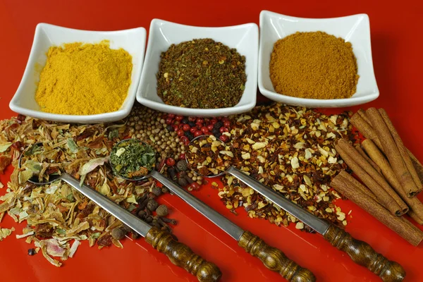 Conjunto de especias y condimentos con cucharas viejas de metal sobre mesa roja — Foto de Stock