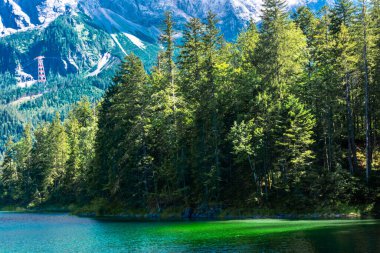 Güneş ışığı altında Zugspitze zirvesinin önündeki turkuaz suyla Eibsee Gölü 'nün muhteşem manzarası. Konum: Eibsee Gölü, Garmisch-Partenkirchen, Bavyera Alpleri, Almanya, Avrupa