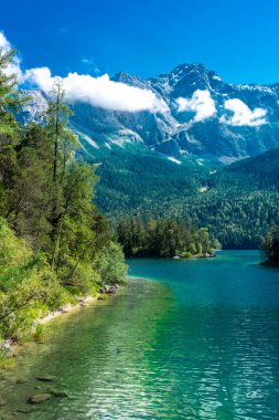 Güneş ışığı altında Zugspitze zirvesinin önündeki turkuaz suyla Eibsee Gölü 'nün muhteşem manzarası. Konum: Eibsee Gölü, Garmisch-Partenkirchen, Bavyera Alpleri, Almanya, Avrupa