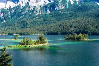 Güneş ışığı altında Zugspitze zirvesinin önündeki turkuaz suyla Eibsee Gölü 'nün muhteşem manzarası. Konum: Eibsee Gölü, Garmisch-Partenkirchen, Bavyera Alpleri, Almanya, Avrupa
