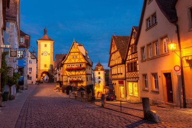 ROTHENBURG OB DER TAUBER, GERMANY, 26 HAZİRAN 2020: Geceleyin tarihi merkezin caddesinde güzel aydınlatılmış yarı keresteli evler