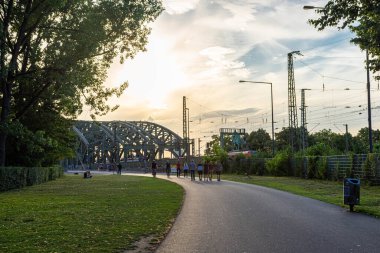COLOGNE, GERMANY, 23 HAZİRAN 2020: İnsanlar Hohenzollern Köprüsü üzerinde güzel gün batımında yürüyorlar