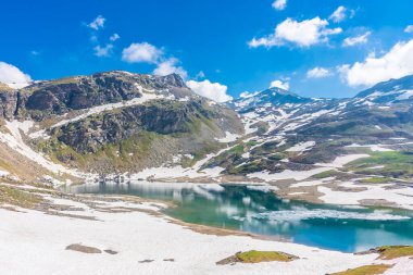 Gran Paradiso Ulusal Parkı 'ndaki karlı arazide güzel zümrüt Alp Gölü
