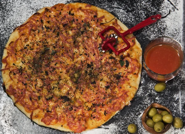 Pizza, kulatý nůž, olivové rajčatová šťáva chutná na černém pozadí — Stock fotografie