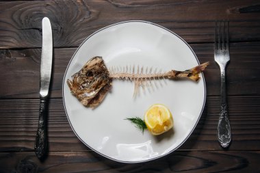 plaka ve sıkılmış limon, bıçak ve çatal balık kemiği