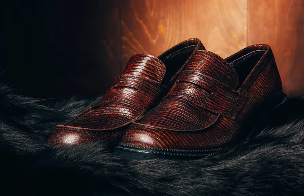 Mocasine (shoes) of snake skin on fur. Fire red wooden backgroun — Stock Photo, Image