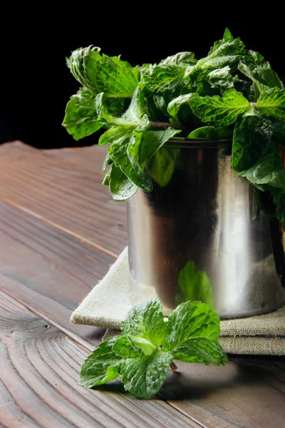 Fresh mint in the stainless cup on the wooden background — Stock Photo, Image