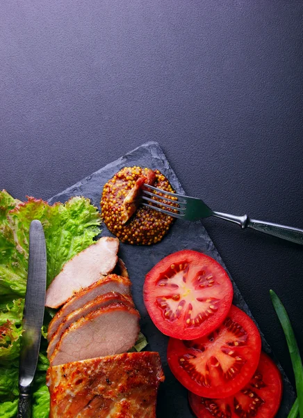 Gebakken varkensvlees filet, ringen van tomaten blad van salade, Franse mosterd — Stockfoto