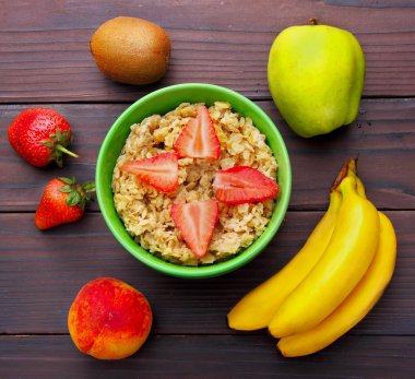 oatmeals in green plate decorated with slice of strawberry. Kiwi