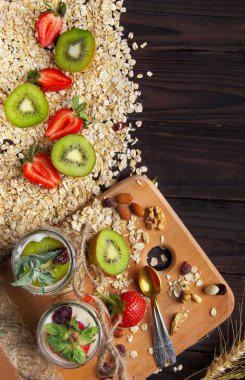 Wooden desk with two jar of granola with kiwi and strawberry . w
