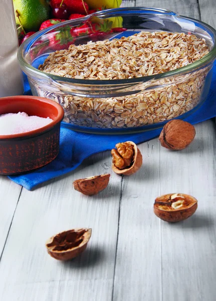 Harinas de avena en cazuela de vidrio, botella de leche, nuez desenfocada en — Foto de Stock