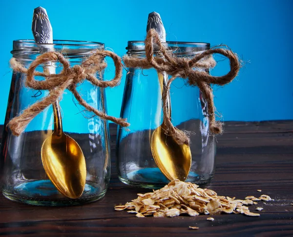 Two empty jar with bronze spoon inside scattered oat flakes and — Stockfoto