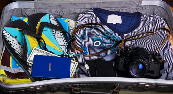 En valise : strings, t-shirt, passeport, argent, appareil photo ; musique — Photo