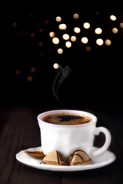 Taza de café en plato blanco y caramelos con vapor .Black backgr —  Fotos de Stock