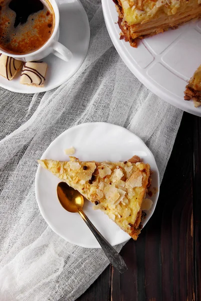 Piece of cake napoleon, puff on white plate, cup with coffe, cna