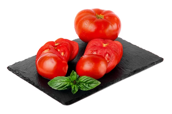 Tomate in Kreise geschnitten mit Basilikumblatt auf Schieferteller. — Stockfoto
