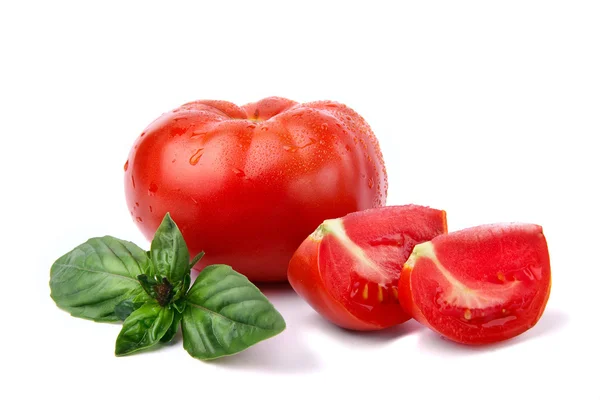 Tomaat, druppels water en kwart van tomaat met blad van basilicum. — Stockfoto
