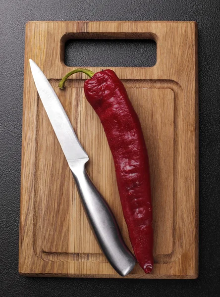 Hot pepper on the wooden desk with stainless steel knife on dark — Stock Photo, Image