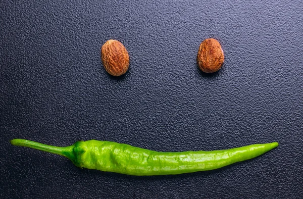 Smilling face from green pepper chili (mouth) and nutmeg(eyes).D — Stock Photo, Image