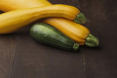 İki büyük ve orta ölçekli küçük yeşil kabak ahşap masa üzerinde sarı. Zuccini ailesi.