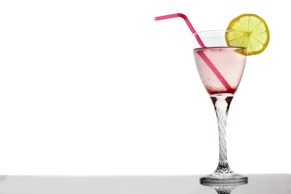 Cocktail di bacche rosa in vetro con limone e tubule su sfondo bianco — Foto Stock