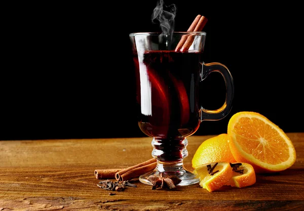 Varm glögg glas med kryddor (canmon pinnar, stjärnanis, torkad citron) på ett träbord. Vertikal bild. Cutted apelsin. Selektivt fokus. — Stockfoto
