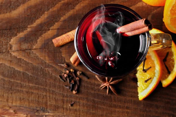 Hot mulled wine glasses with spices (canmon sticks, star anise, dried lemon) on a wooden table.Vertical shot.Cutted orange.Selective focus.Top view.Focus on glass — Stock Photo, Image