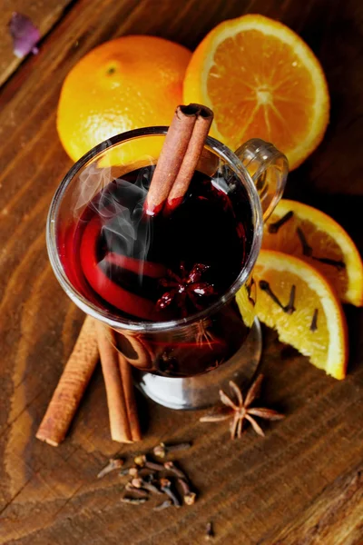 Hot mulled wine glasses with spices (canmon sticks, star anise, dried lemon) on a wooden table.Vertical shot.Cutted orange.Selective focus.Top view.Focus on glass — Stock Photo, Image