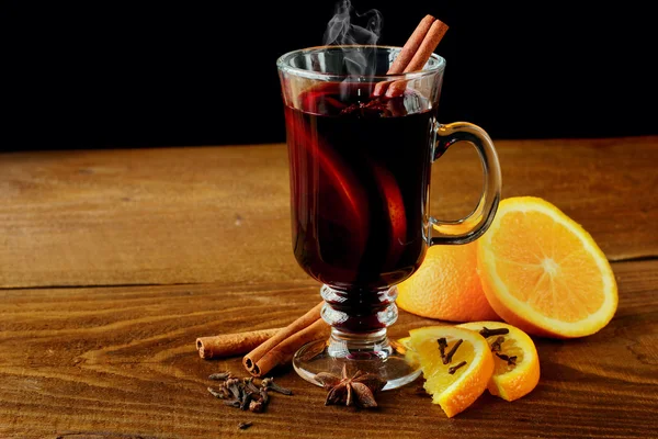 Varm glögg glas med kryddor (canmon pinnar, stjärnanis, torkad citron) på ett träbord. Vertikal bild. Cutted apelsin. Selektivt fokus. — Stockfoto