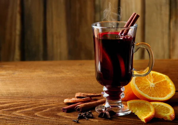 Hot mulled wine glasses with spices (canmon sticks, star anise, dried lemon) on a wooden table.Vertical shot.Cutted orange.Selective focus. — Stock Photo, Image