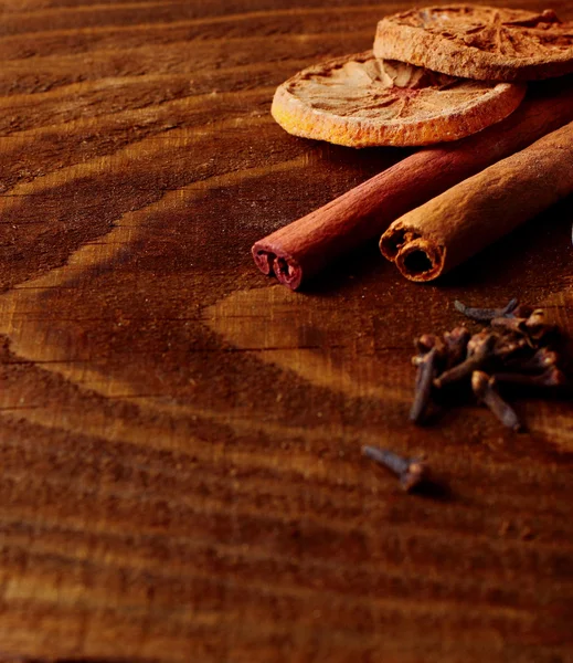 Cynamon laski suszone cytryny i goździk rozmyte na drewnianym stole. Przyprawy. selektywne skupienie — Zdjęcie stockowe