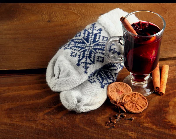 Hot mulled wine with species, dried lemon and cinamon sticks.Winter gloves.wooden background — Stock Photo, Image
