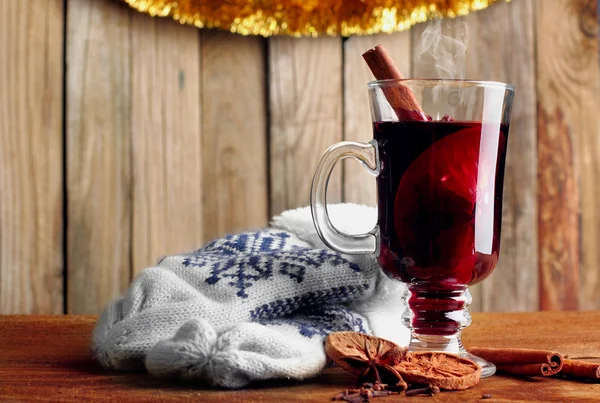 Hot mulled wine with species, dried lemon and cinamon sticks.Winter gloves.wooden background — Stock Photo, Image