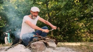 Adam odunları kırıp ateşe atıyor. Seyahat Konsepti Bisikletçi Hafta Sonu Ormanı Doğa Arkaplanını Harcar