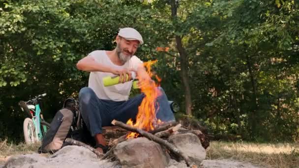 현관을 수염을 기르고 불옆에 사람이 보온병에서 붓는다 클로즈업 숲에서의 자연계의 — 비디오
