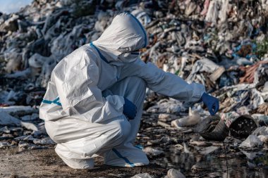 People in protective gear are inspecting trash at a landfill, taking steps to manage waste and reduce environmental pollution effectively.