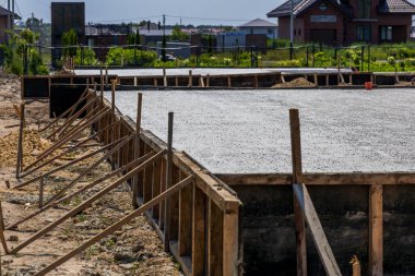 Workers pour cement to create a solid foundation for a new home in a developing neighborhood, showcasing construction progress.