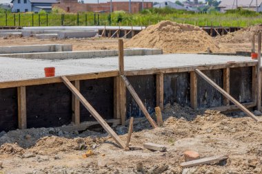 Cement is being poured to create the foundation for a house in a developing area, showcasing the groundwork for future construction.